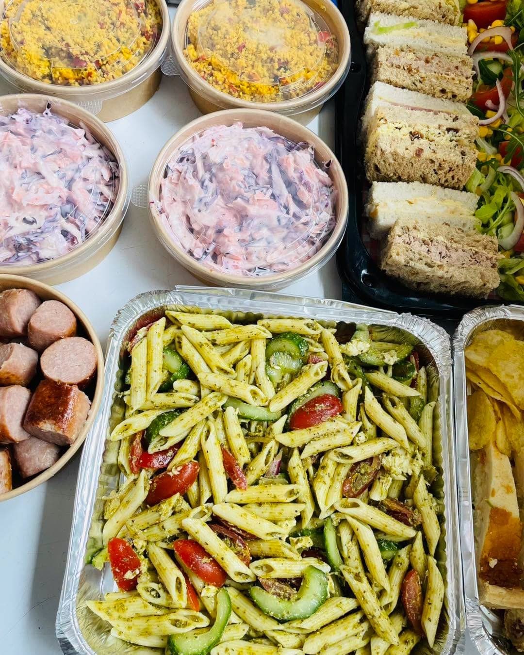 A buffet of pasta salad, coleslaw and sandwiches
