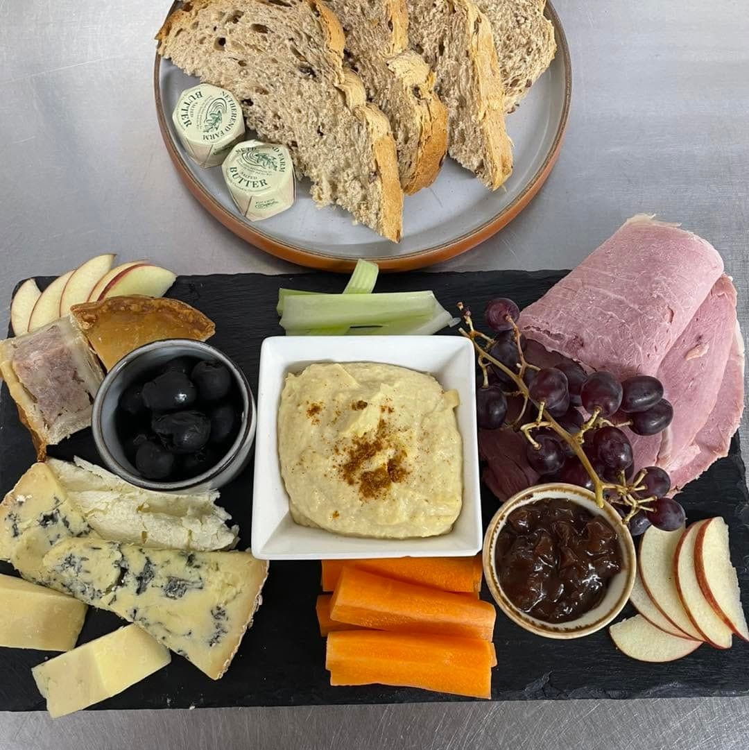 A cheese board with dips, grapes and crackers