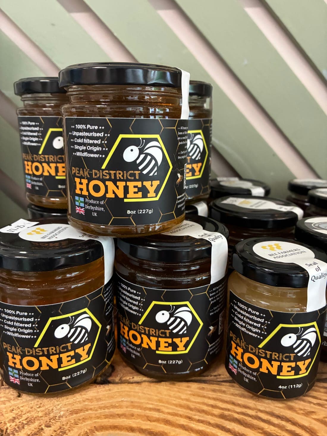 Jars of Peak District Honey stacked on a wooden shelf