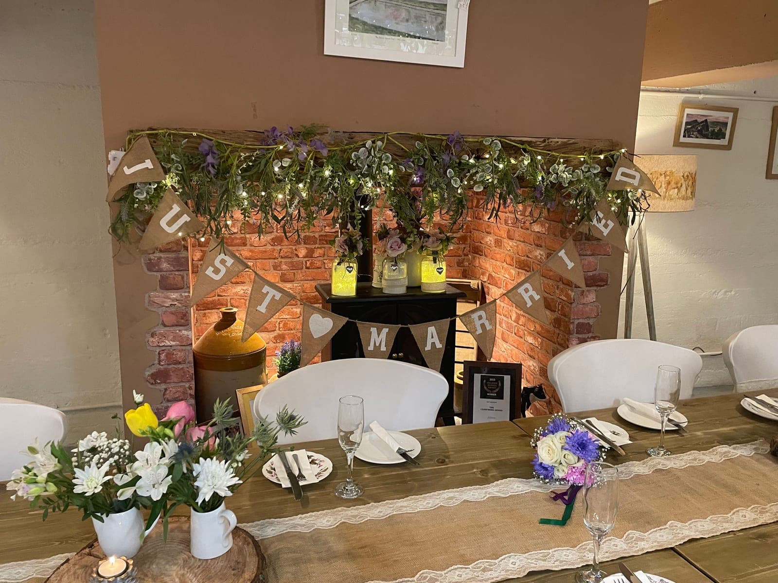 A wedding celebration table set for afternoon tea, with Just Married bunting over the fireplace