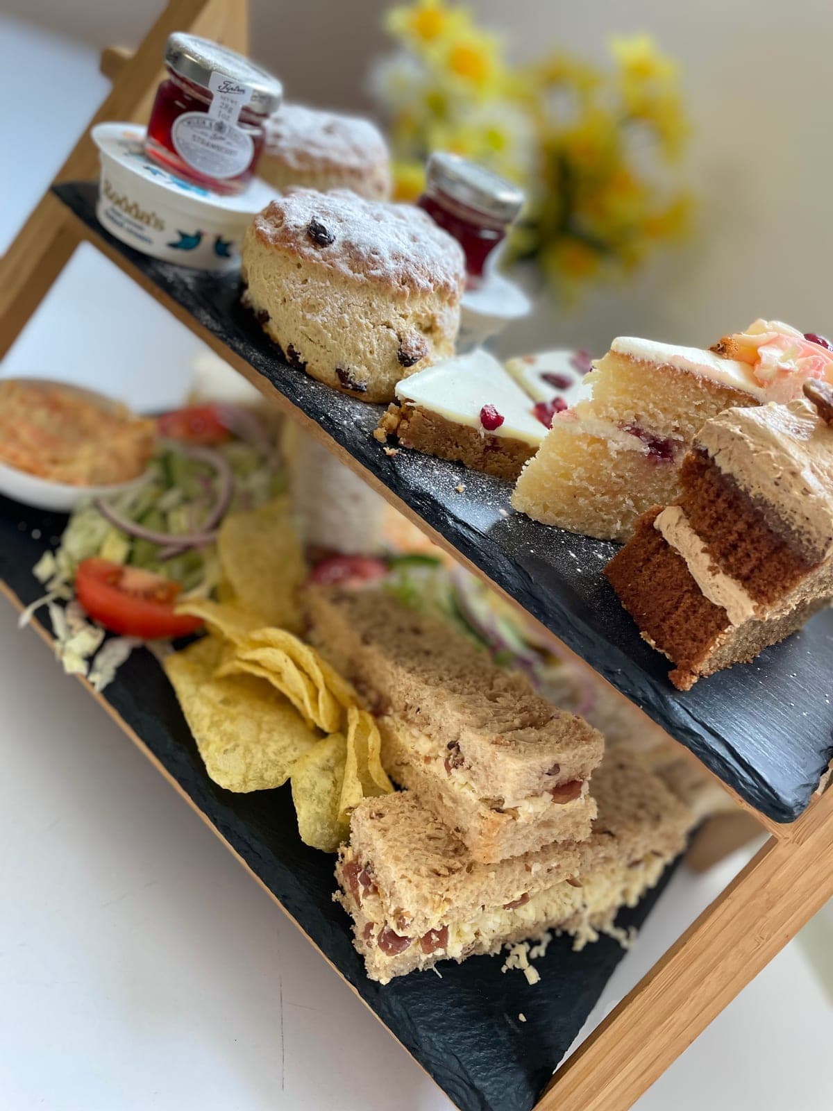 An afternoon tea stand with sandwiches, scones and cakes