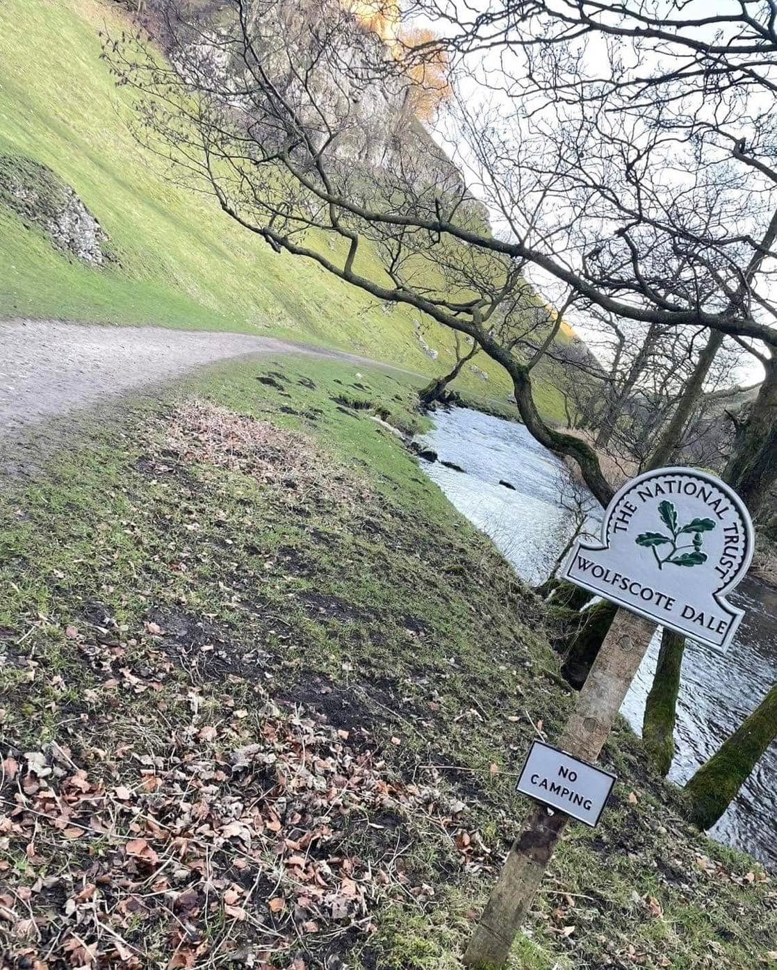 A wooden footpath sign beside a stream in the dales