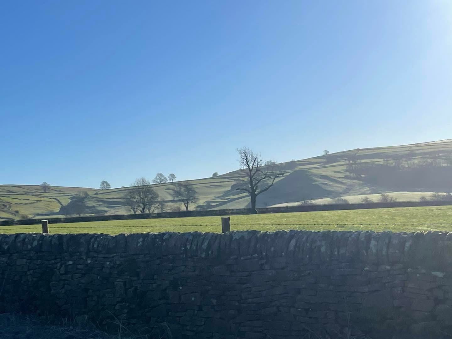 Rolling White Peak fields and drystone walls under a blue sky